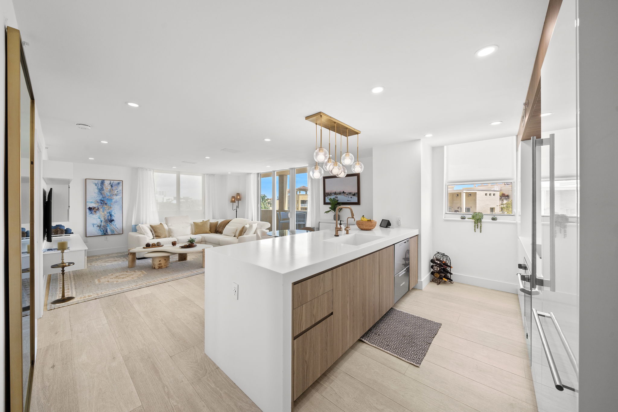 Open-plan kitchen and living area with walnut island and gold pendant lighting